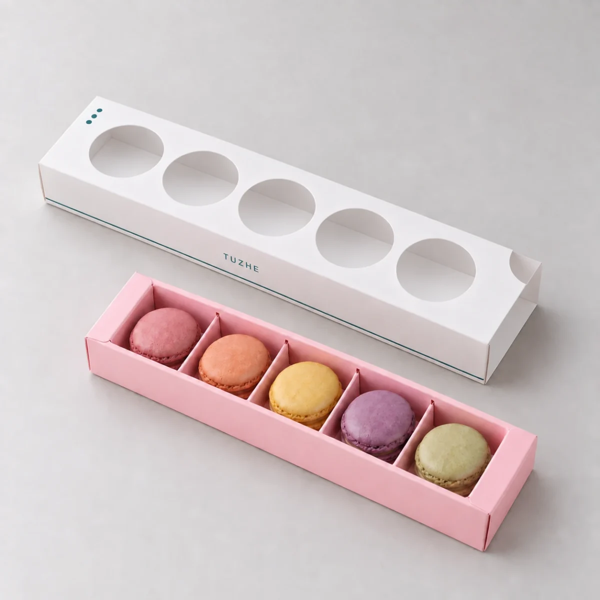 AI design concept: empty white five-window sleeve beside one pink tray with four dividers and five sample macarons