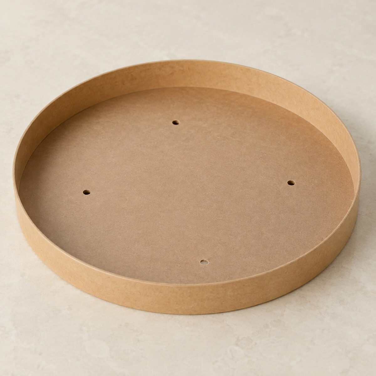 Underside of a round kraft paper lid with a shallow rim and four small vent holes