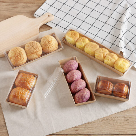 Kraft pastry trays with clear covers holding muffins choux buns and purple pastries