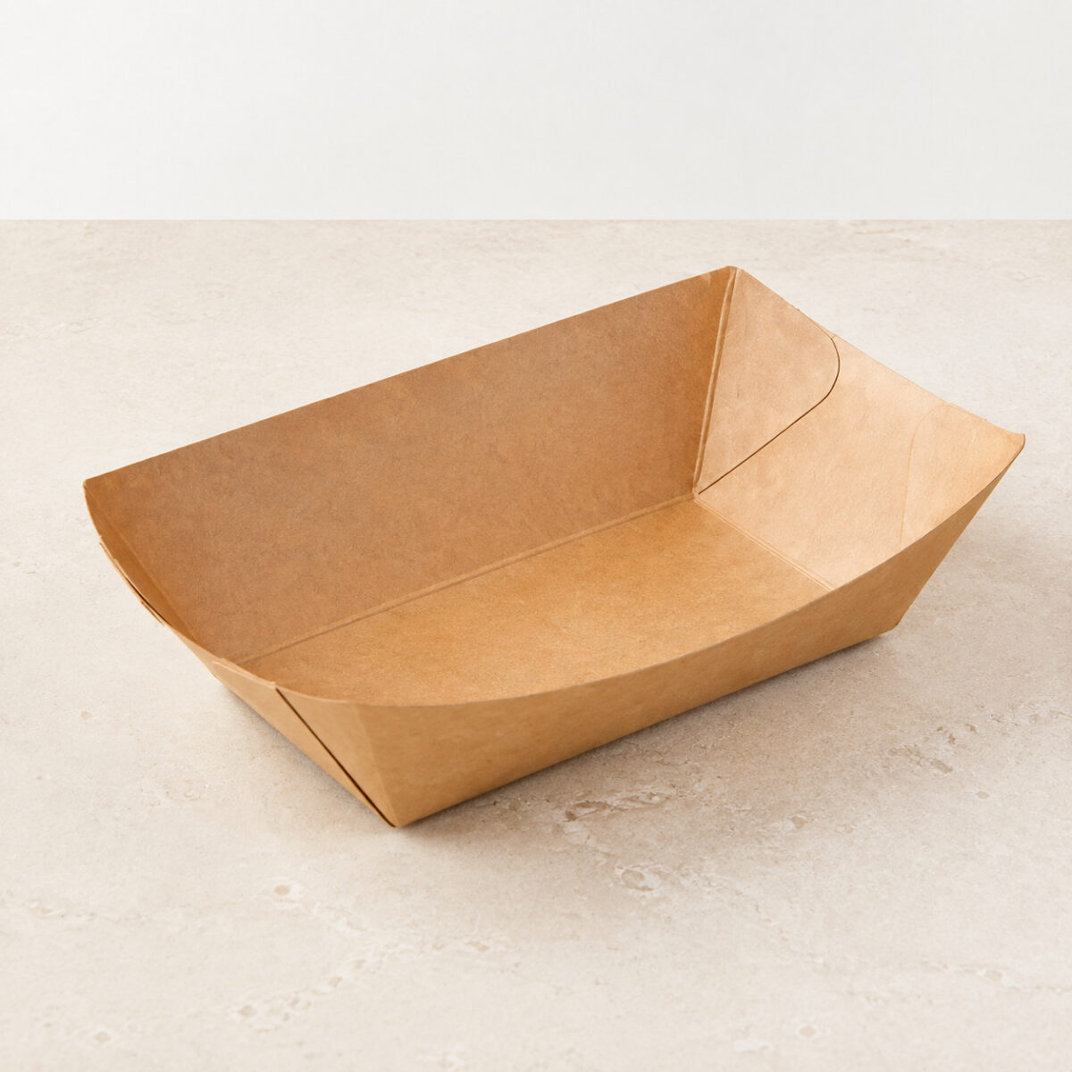 Empty kraft paper food boat tray with folded curved corners on a light stone surface