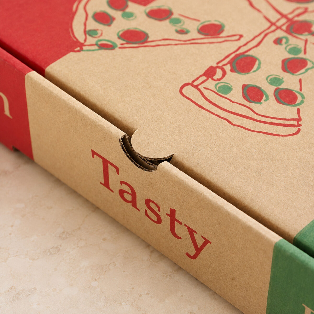 Close-up of a kraft pizza box thumb notch, rounded lid tab and corrugated edge