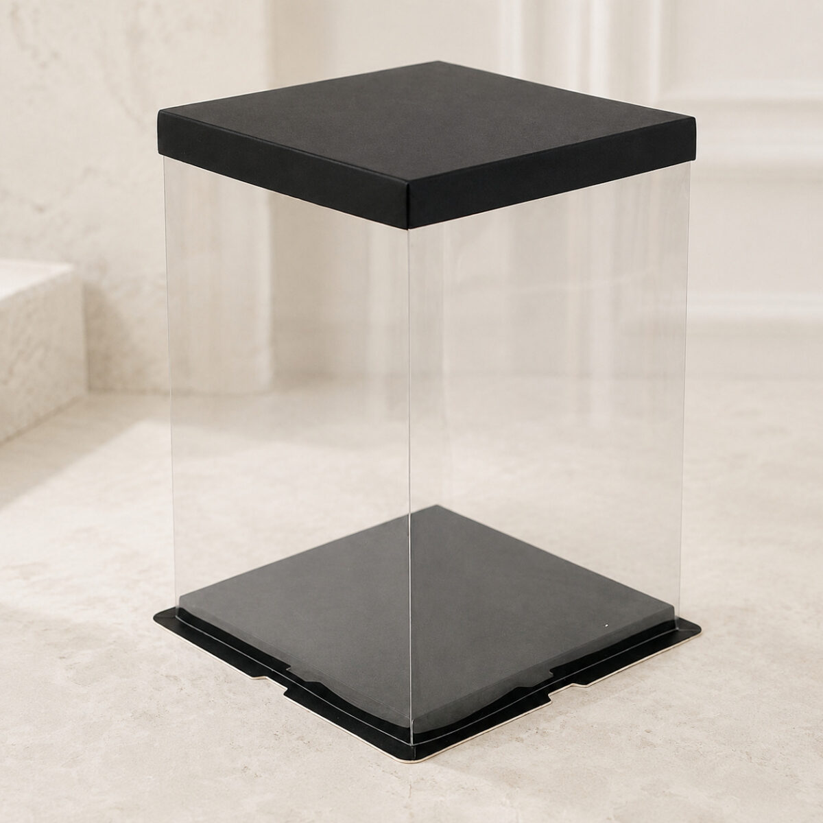 Tall empty clear square cake box with a black flat lid and notched black base flange