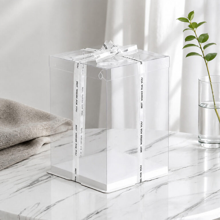 Tall transparent square cake display box with a white base and Best Wishes for You ribbon