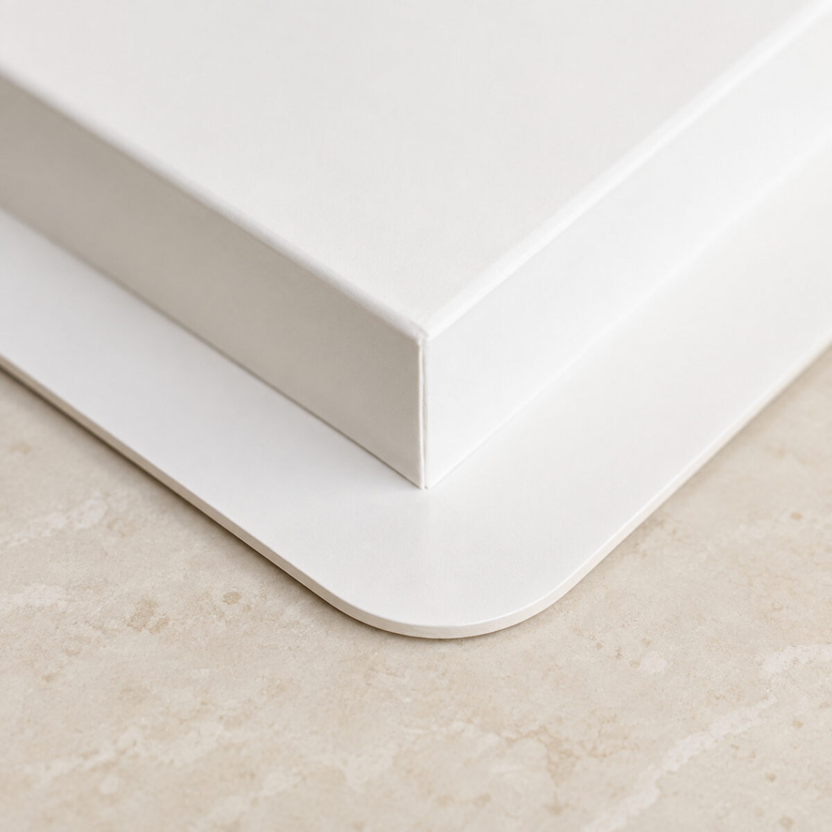 Close-up of a white cake box base with a folded side and broad rounded bottom flange