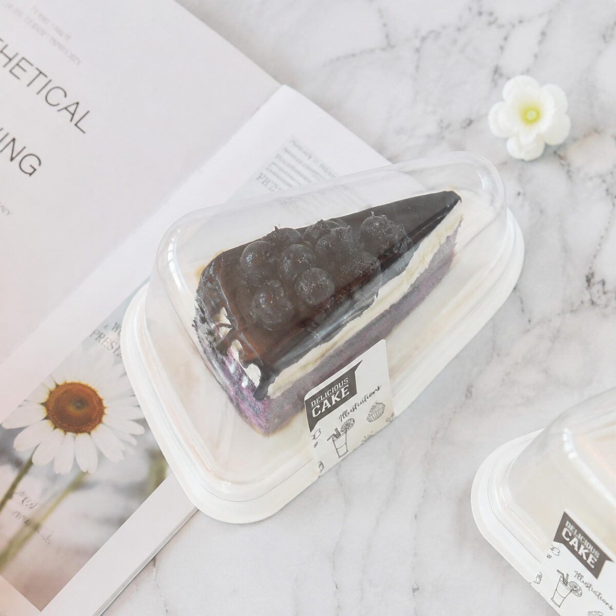 Triangular Cake Slice Boxes with Clear Lids Clear triangular cake slice box with a white base and chocolate layer cake on a marble table