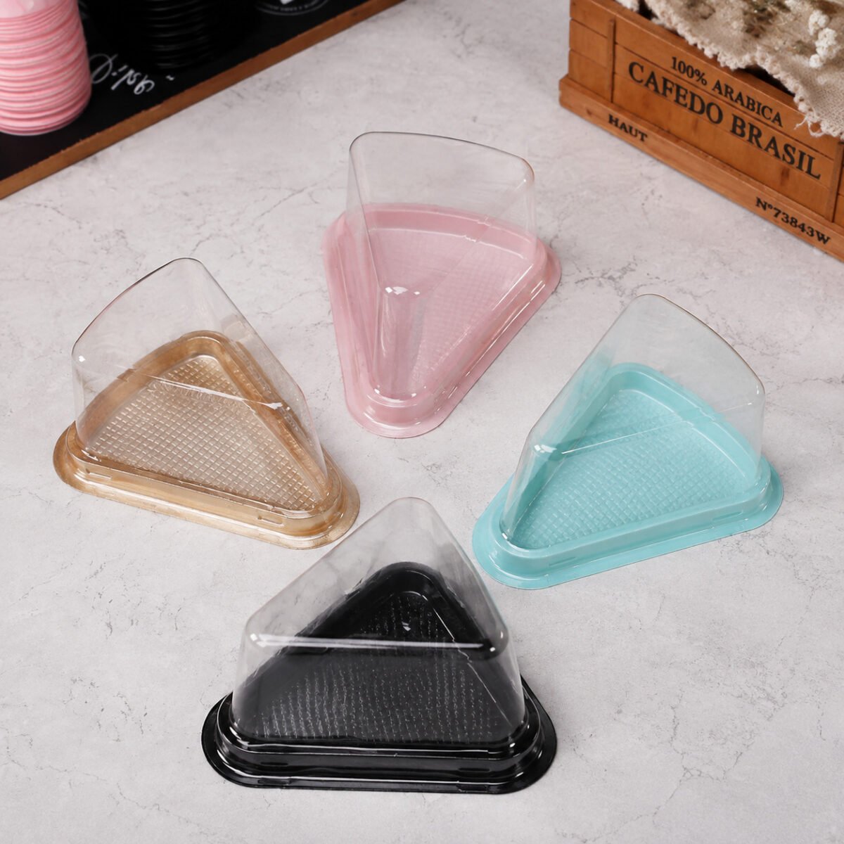 Triangular Dessert Containers with Colored Bases Four clear triangular cake slice containers with gold, pink, turquoise and black bases