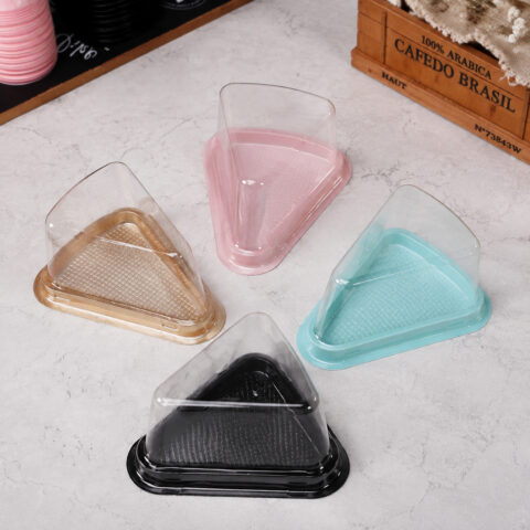 Triangular Dessert Containers with Colored Bases Four clear triangular cake slice containers with gold, pink, turquoise and black bases
