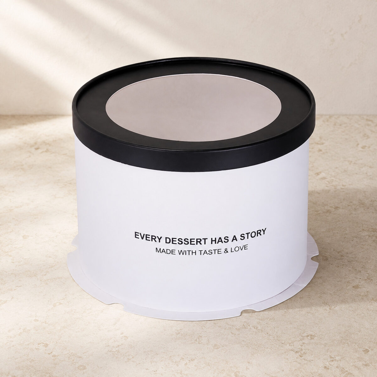 White cylindrical cake box with a black window lid and Every Dessert Has a Story front printing