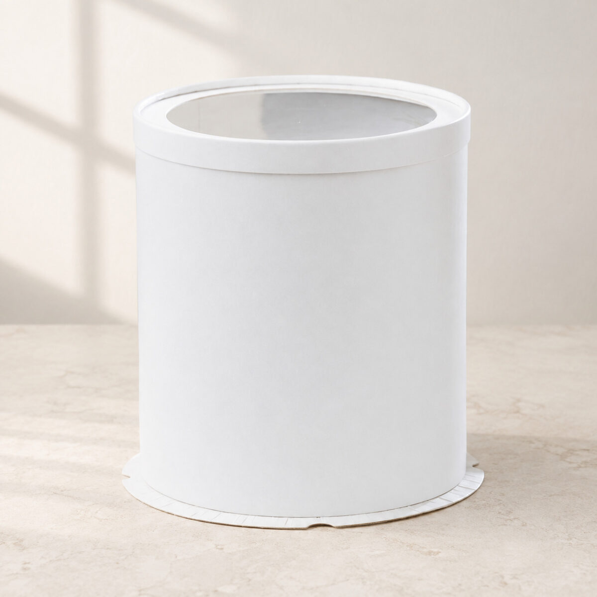 Tall plain white cylindrical cake box with a round clear window in its white lid