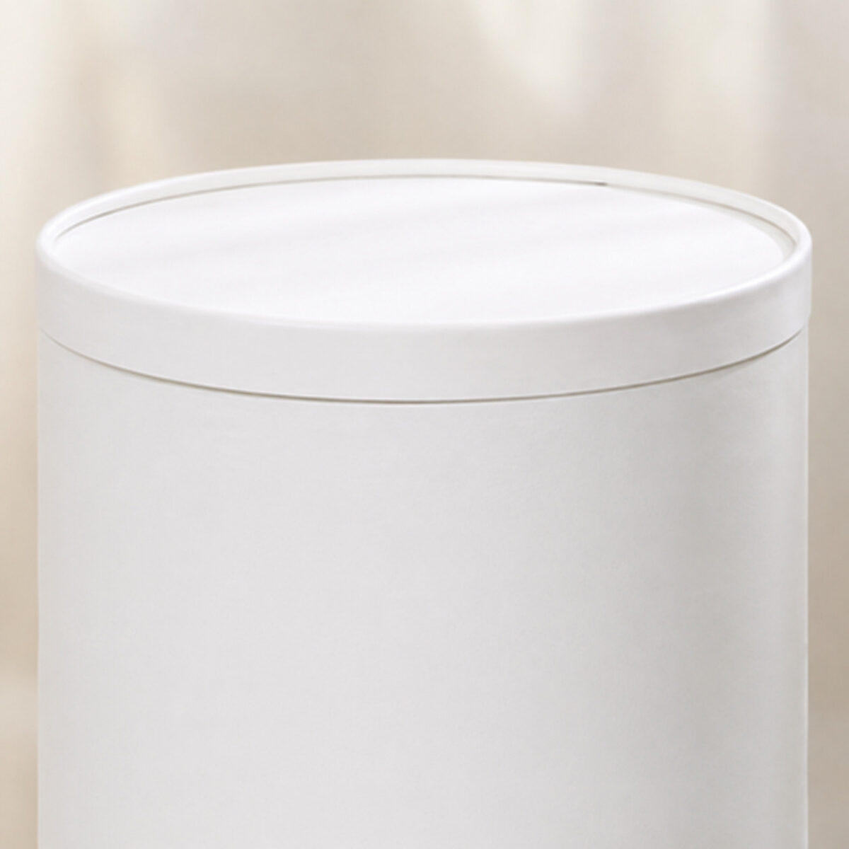 Close-up of a solid white circular cake box lid and its upper body seam