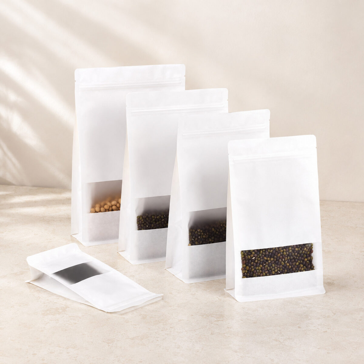 Four filled white window stand-up pouches beside one empty flat pouch