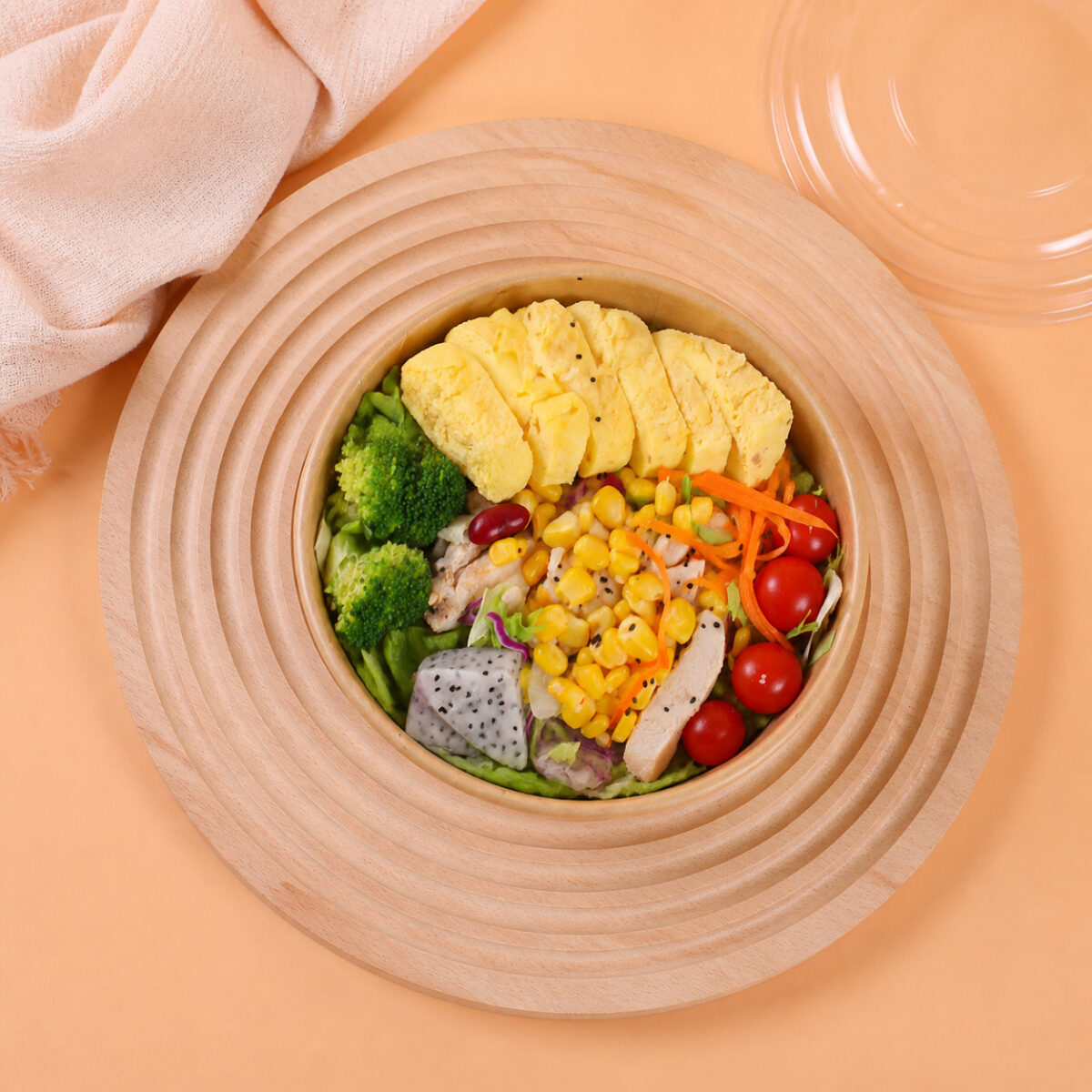Wide Kraft Salad Bowls with Clear Lid Options Wide kraft salad bowl with vegetables, chicken and sliced omelet on a round wooden tray beside a clear lid