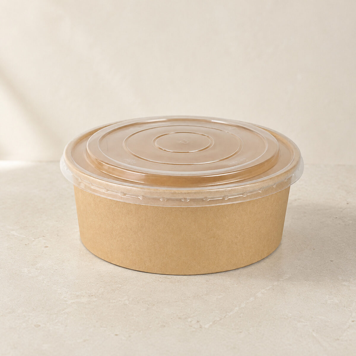 Shallow round kraft paper food bowl with a clear snap-on lid and concentric molded rings